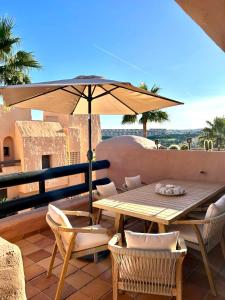 a wooden table and chairs with an umbrella on a patio at Sweet Home II in Manilva
