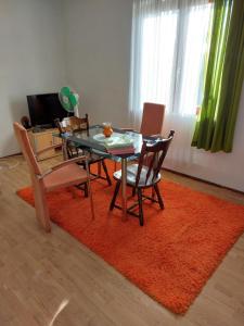 a dining room with a table and chairs on a red rug at Rajj in Bela Crkva