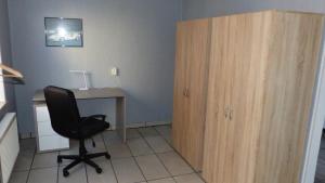 a room with a desk and a chair next to a wooden cabinet at Haus am Bahndamm in Holzminden