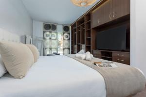 a bedroom with a large white bed with a flat screen tv at Sunstay Chalet La Colina Torremolinos in Torremolinos +30 photos