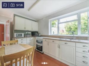 a kitchen with white cabinets and a table and a window at Archtrees House - Family home in Surrey village in Lingfield +17 photos