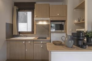 a kitchen with wooden cabinets and a counter top at Le Castel des Roches - Sejour ski & spa in Saint-Gervais-les-Bains