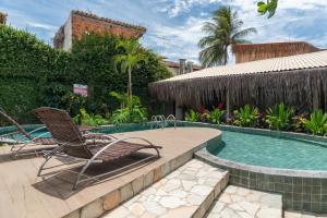 a swimming pool with two chairs next to a house at Pousada Sempre Graciosa in Praia do Frances