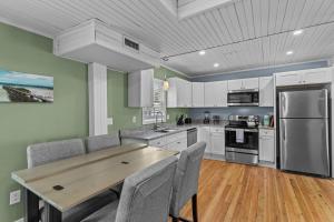 a kitchen with white cabinets and a wooden table at Portsmouth Beach cottage in Portsmouth +25 photos