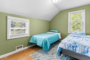 two beds in a room with green walls and windows at Portsmouth Beach cottage in Portsmouth