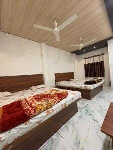 two beds in a bedroom with a ceiling at Hotel Shree Siddhi vinayak in Ujjain