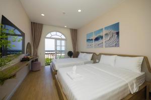 a bedroom with two beds and a large window at Lotus Home Cafe - Cable Car Station in Phú Quốc
