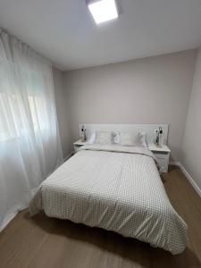 a white bedroom with a bed and white curtains at mar in Moaña