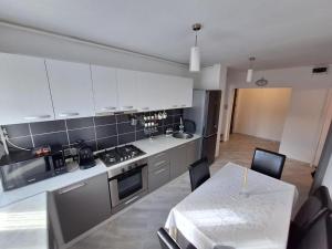 a kitchen with white cabinets and a table and a dining room at Biverse Prestige in Petrila