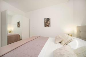 a white bedroom with a large bed with two pillows at Carpe Diem in Raslina
