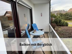 - un balcon avec deux chaises bleues et une table dans l'établissement FeWo Berg-Domizil Altenau inklusive Bettwäsche und Handtüchern, à Altenau