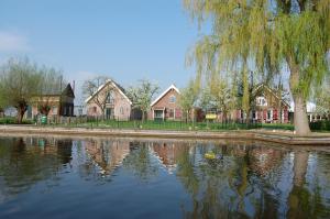 um reflexo de casas na água com uma árvore em De Willigen Logies em Vreeland