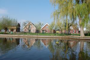 a reflection of houses in the water with a tree at De Willigen Logies in Vreeland