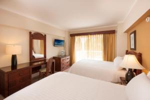 a hotel room with two beds and a desk and a mirror at Occidental Caribe - All Inclusive in Punta Cana