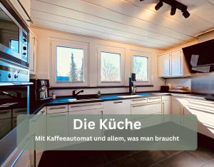 a kitchen with white cabinets and three windows at Lounge94 - Luxus auf 180 m2 in Wilhelmshaven