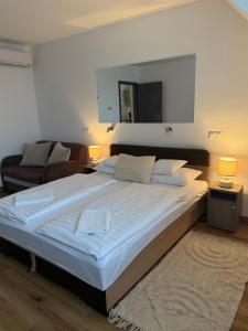 a bedroom with a large bed and a couch at Ferzs Apartman Egerszalók in Egerszalók