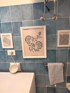 a bathroom with a picture on a blue tiled wall at Appartamento Nora in Campese