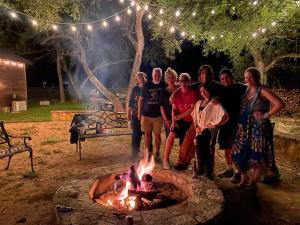 un grupo de personas de pie alrededor de un pozo de fuego en Cabin 6 The Roost Cabins, en Lakehills
