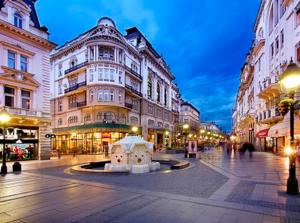 a city street at night with buildings and a fountain at Apartment Centro in Belgrade