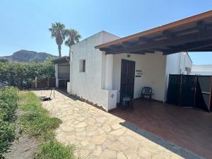 a small white house with a porch and a patio at Villa by the Vulcano - 70mq plus large garden and patio in Vulcano