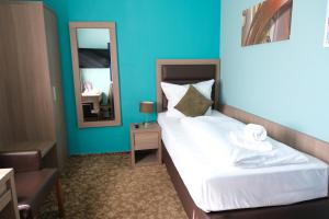 a hotel room with a bed and a mirror at easy&cosy-Hotel Moers-Mitte in Moers