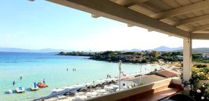 a beach with umbrellas and people in the water at Cottage DeLuxe in Golfo Aranci