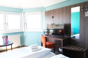 a room with a bed and a desk with a television at easy&cosy-Hotel Moers-Mitte in Moers