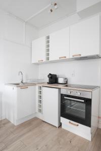 une cuisine avec des armoires blanches et un four à plaques de cuisson dans l'établissement Appartement Moderne et Équipé aux Portes de Paris, à Aubervilliers 13 autres photos