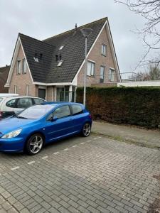 un coche azul estacionado en un estacionamiento frente a una casa en Apartment Hoorn Suburb - Extended stays by Haring Verhuur, en Hoorn