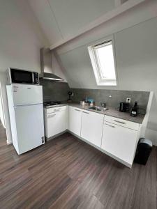 Una cocina con un refrigerador blanco y un fregadero. en Apartment Hoorn Suburb - Extended stays by Haring Verhuur, en Hoorn