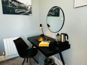 a black desk with a mirror and a chair at The Chesterhouse in Douglas
