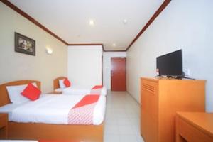a hotel room with a bed and a tv at Hotel O London in Sandakan