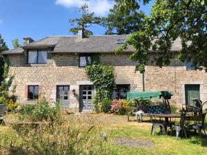 a stone house with a table and chairs in front of it at 224 Rue St Martin in Montbray