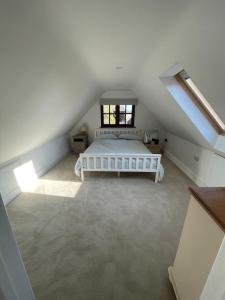 a bedroom with a white bed in a attic at The Old Poor House Coach House in Sidlesham