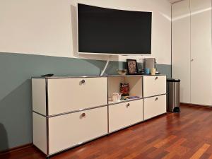 a white entertainment center with a flat screen tv on top at Exklusives City Studio in Neuhausen - stilvoll wohnen nahe Schloss Nymphenburg in Munich