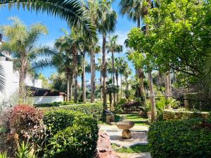a garden with palm trees and a fountain at Ksar Rimal par Immo Marina Vacances de Rêve MF in Marina Smir