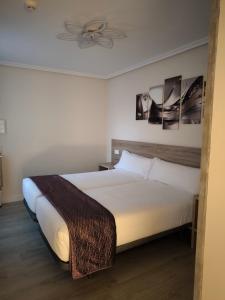オビエドにあるHostal del Norteの白いシーツが敷かれた大きなベッドのある寝室