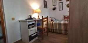 Una habitación con un escritorio con lámpara y una cama. en Casa Tejar, en Almería