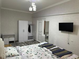 a bedroom with a bed and a flat screen tv at Toxir Guest House in Samarkand