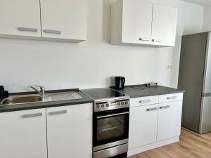a kitchen with white cabinets and a stove and a sink at Monteurwohnung und Ferienwohnung Philippsburg in Philippsburg