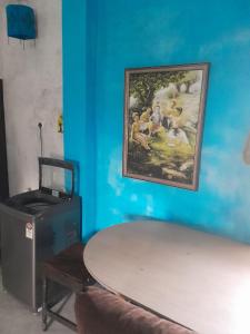 a painting hanging on a blue wall with a table at Ganga river House in mayapur