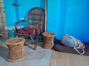 a chair and two wicker chairs and a table at Ganga river House in mayapur