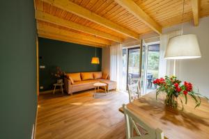 a living room with a couch and a table with flowers at Leno Tu - Domki przy jeziorze z sauną i banią in Ciemno