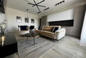a living room with two couches and a table at Gold Apartamentai Mano Jūra 2 in Palanga