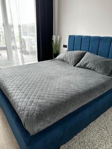 a blue bed with a blue headboard in a bedroom at Gold Apartamentai Mano Jūra 2 in Palanga