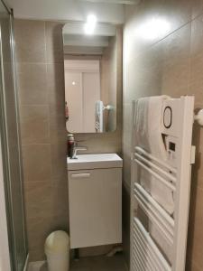 Un baño pequeño con lavabo y espejo. en Ton petit coin de paradis avec balcon au Trouville Palace, en Trouville-sur-Mer 22 fotos más