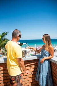 a man and a woman standing at a counter near the beach at Acuario Pousada in Arraial do Cabo