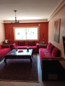 ein Wohnzimmer mit roten Sofas und einem Tisch in der Unterkunft Appartement de luxe Résidence Majorelle in Marrakesch