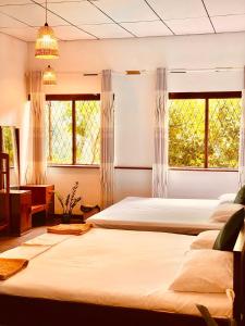 two beds in a room with two windows at Richiland Tea Estate Bungalow in Deniyaya