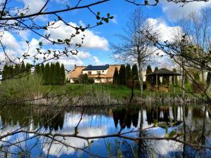 a view of a house from the lake at SIEDLISKO GąSKA in Maszewko